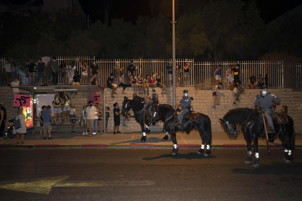 Israeli police officers on horseback stand in front of Israeli protesters during a demonstration against lockdown measures that they believe are aimed at curbing protests against Prime Minister Benjamin Netanyahu, in Tel Aviv, Israel, Thursday, Oct. 1, 2020. (AP Photo/Sebastian Scheiner)