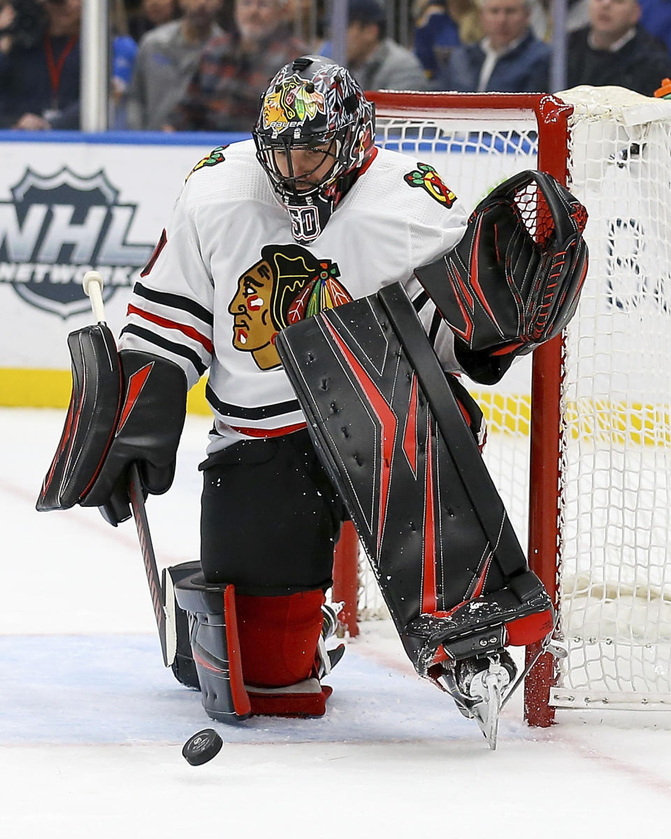 Chicago Blackhawks goaltender Corey Crawford (50) deflects the puck during the second period of an NHL hockey game against the St. Louis Blues Tuesday Feb. 25, 2020, in St. Louis. (AP Photo/Scott Kane)