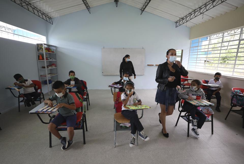 Wearing masks to curb the spread of the new coronavirus, students attend class in the one open school in Campohermoso, Colombia, Thursday, March 18, 2021. Campohermoso is one of two municipalities in Colombia that has not had a single case of COVID-19 since the pandemic started one year ago, with the student body at the school rotating half the students into their classrooms while the other attends via the internet. (AP Photo/Fernando Vergara)