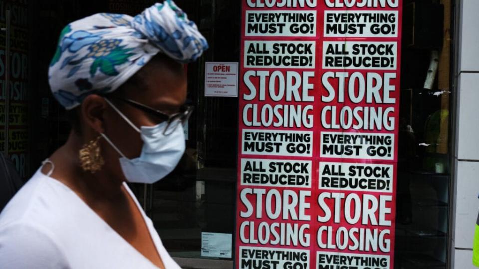 Black woman in front of "Store Closing" sign on business, theGrio.com