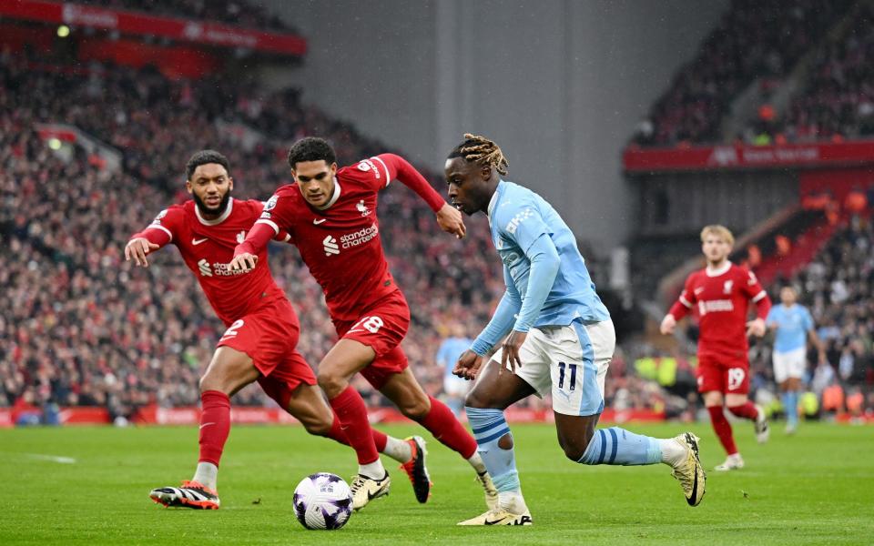 Jeremy Doku of Manchester City runs with the ball whilst under pressure from Joe Gomez and Jarell Quansah