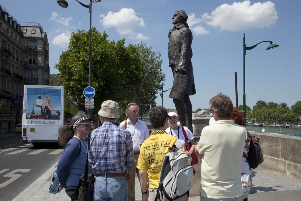 In this photo taken Friday, July 19, 2013, tourists gather around the Thomas Jefferson Statue next to Musée d'Orsay during a Guided Tour around the main spots of the Revolutonary-era American presence on Paris' left bank, in Paris, France. (AP Photo/Francois Mori)