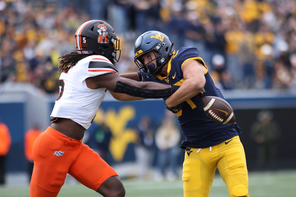 Oklahoma State's Kendal Daniels, left, forces a fumble by West Virginia's Kole Taylor, right, after a catch during the first half of an NCAA college football game Saturday, Oct. 21, 2023, in Morgantown, W.Va. (AP Photo/Chris Jackson)