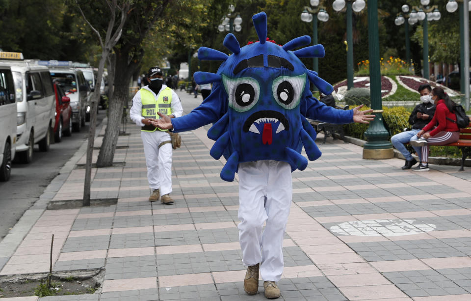 Un policía vestido con un disfraz que representa el virus COVID-19 camina por el Paseo El Prado como parte de una campaña de concientización sobre la propagación del nuevo coronavirus en La Paz, Bolivia, el miércoles 10 de febrero de 2021. (AP Foto/Juan Karita)