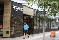 A person wearing a mask jogs past an Amazon Go store, Thursday, April 30, 2020, in downtown Seattle. Amazon.com is expected to announce earnings for the first quarter of 2020 at the close of markets Thursday, a report that is expected to be closely watched due to the effects of the coronavirus outbreak on the company. (AP Photo/Ted S. Warren)