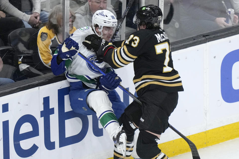 Vancouver Canucks center Nils Aman (88) is sent against the boards by Boston Bruins defenseman Charlie McAvoy (73) during the first period of an NHL hockey game Thursday, Feb. 8, 2024, in Boston. (AP Photo/Steven Senne)