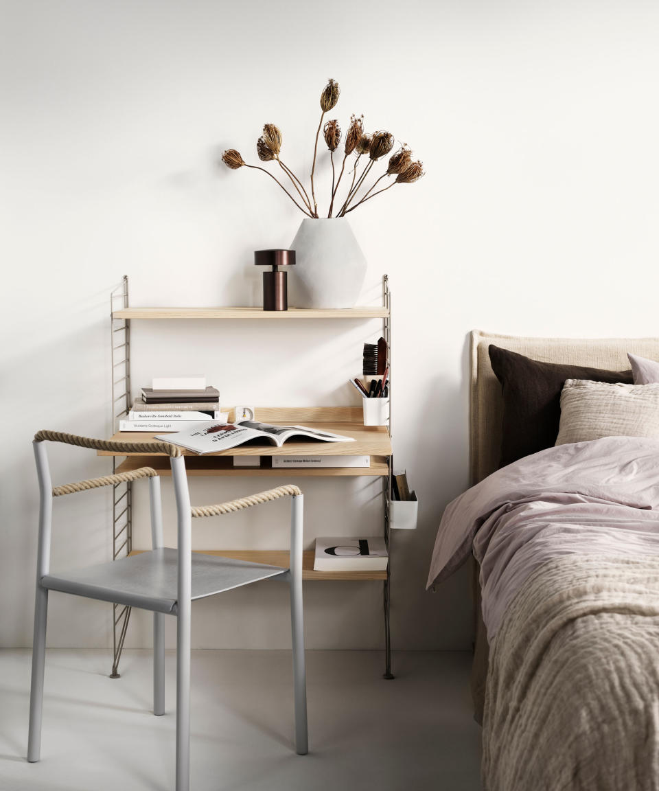 Bedroom with string furniture shelving unit with desk area, chair with rope style arms, positioned beside bed