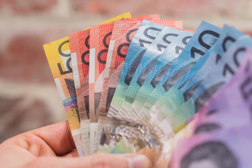 handful of Australian cash with a brick background