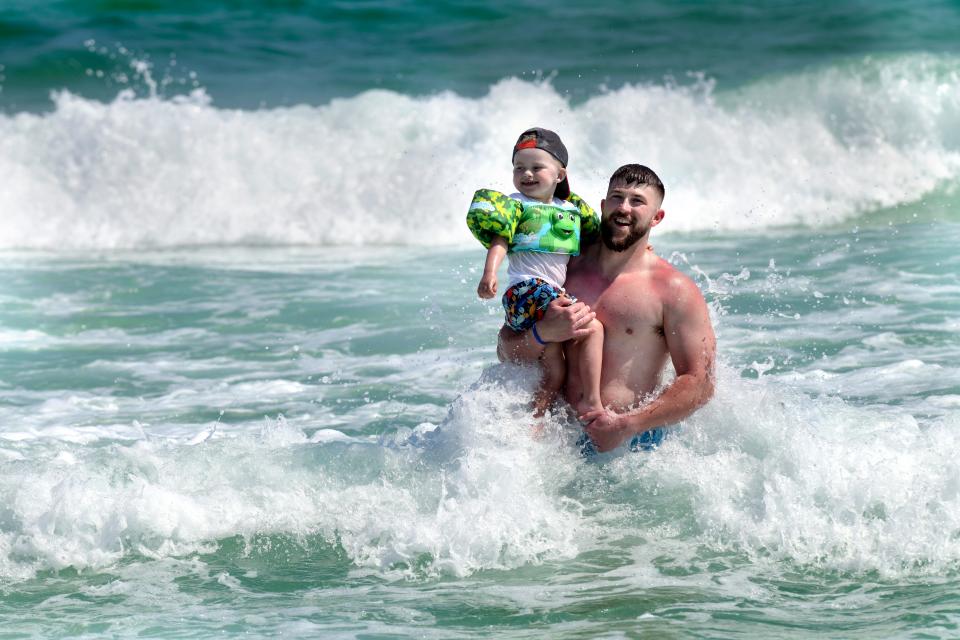 Cameron Jones and his son, Nash, enjoy the surf Monday at the Miramar Beach Regional Access on Scenic Gulf Drive in Walton County. The county's tourist season has been safer than last year so far, with fewer public assist calls and no swimming fatalities.
