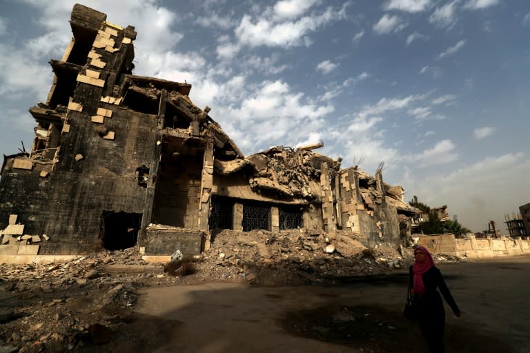 A woman walks past a devastated building in the Syrian city of Raqa on October 13, 2018
