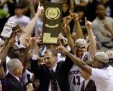 University of Connecticut head coach Jim Calhoun holds the NCAA national championship trophy high after his team defeated Duke University 77-74, March 29. The Huskies won their first-ever NCAA national championship at Tropicana Field in St. Petersburg. At right is Huskies' center Jake Voskuhl (43). JLS/HB/JDP