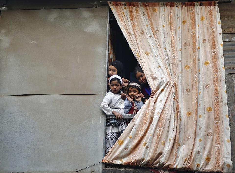 Muslim children peep through an opening of their house to watch a religious procession to mark Eid-e-Milad-ul-Nabi, or birthday celebrations of Prophet Mohammad, in Delhi