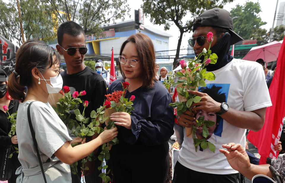 Pro-democracy activists, from second left, Panupong Jadnok, Panusaya Sithijirawattanakul and Jatupat Boonpattararaksa receive a flower from a supporter as they arrived at the Attorney General office in Bangkok, Thailand, Monday, March 8, 2021. Prosecutors in Thailand charged 18 pro-democracy activists with sedition on Monday, while lodging additional charges of insulting the monarchy against three of them. (AP Photo/Sakchai Lalit)