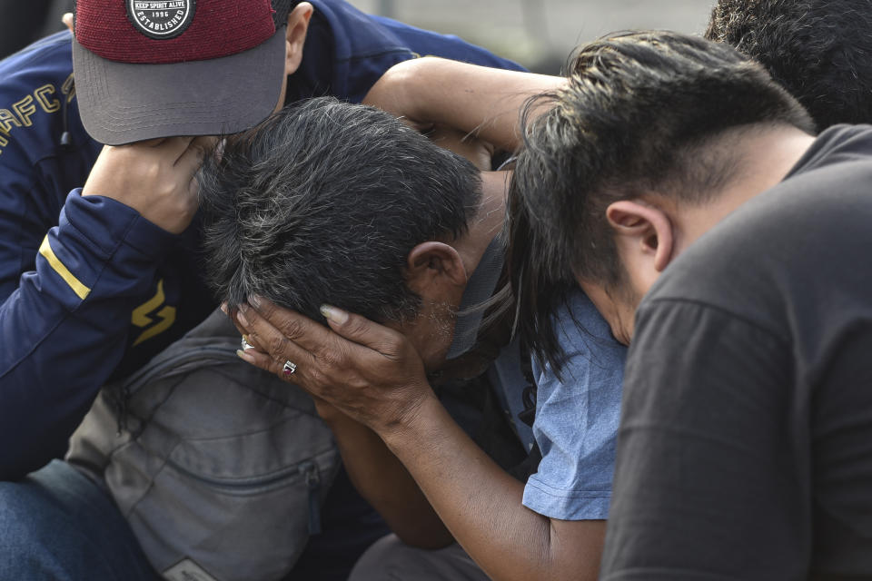 Men weep as they offer prayer outside Kanjuruhan Stadium where a soccer stampede killed more than 100 people on Saturday, in Malang, East Java, Indonesia, Tuesday, Oct. 4, 2022. Police firing tear gas inside the stadium on Saturday in an attempt to stop violence after an Indonesian soccer match triggered a disastrous crush of fans making a panicked, chaotic run for the exits, leaving at a number of people dead, most of them trampled upon or suffocated. (AP Photo/Dicky Bisinglasi)