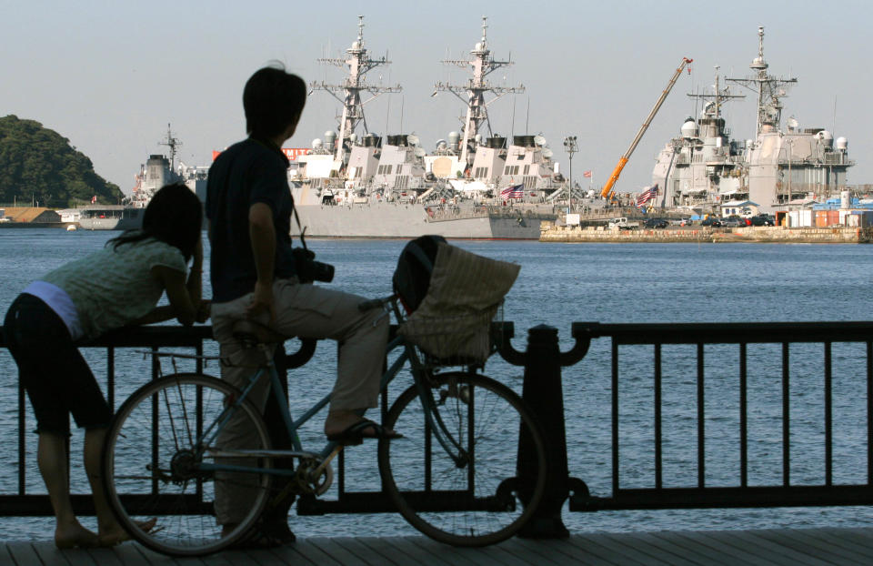 FILE - This Oct. 9, 2006 file photo shows a local resident couple looking at a fleet of ships, part of Kitty Hawk's battle group at Yokosuka Naval Base in Yokosuka, south of Tokyo. An Associated Press investigation into the military’s handling of sexual assaults in Japan has found a pattern of random and inconsistent judgments in which most offenders are not incarcerated. Instead, commanders have ordered “nonjudicial punishments” that ranged from docked pay to a letter of reprimand. (AP Photo/Shuji Kajiyama, File)