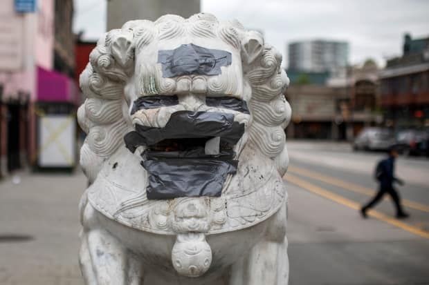 Racist graffiti is covered up by duct tape on the lions at the Millennium Gate in Chinatown in May 2020.