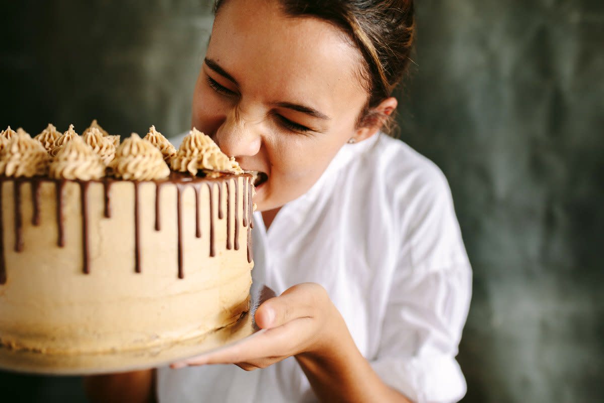 A professional baker takes a bite out of her chocolate ganache cake.