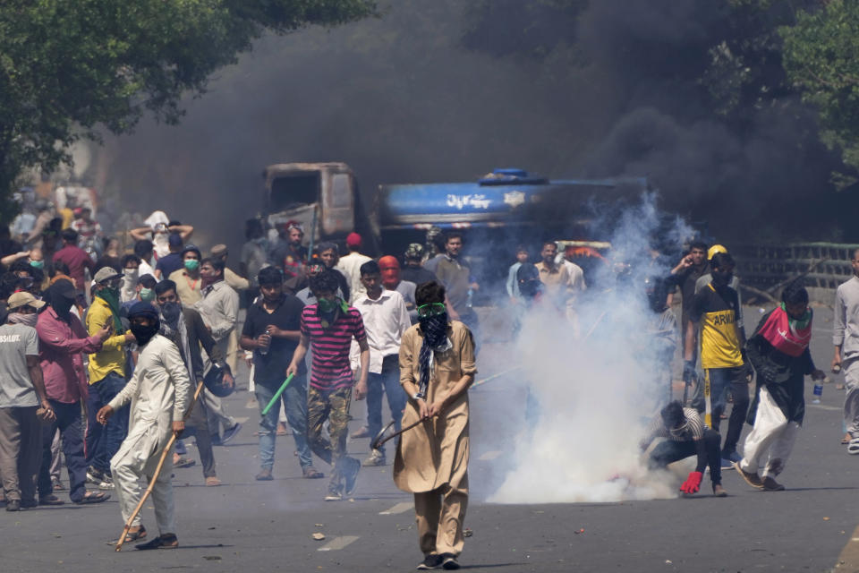 Supporters of Pakistan's former Prime Minister Imran Khan remove tear gas shell fired by police to disperse them during a protest against the arrest of their leader, in Lahore, Pakistan, Wednesday, May 10, 2023. Khan can be held for eight days, a court ruled Wednesday, a day after the popular opposition leader was dragged from a courtroom and arrested on corruption charges, deepening the country's political turmoil. (AP Photo/K.M. Chaudary)