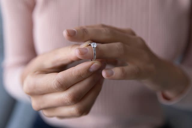 <p>Getty</p> A woman removing an engagement ring from her finger