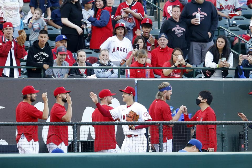 Angels starting pitcher Shohei Ohtani (17) high-fives teammates in the bullpen.