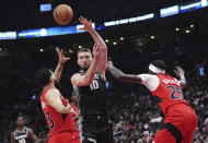 Sacramento Kings forward Domantas Sabonis (10) passes the ball as Toronto Raptors guard Fred VanVleet (23) and forward Chris Boucher (25) defend during the second half of an NBA basketball game in Toronto on Wednesday, Dec. 14, 2022. (Nathan Denette/The Canadian Press via AP)