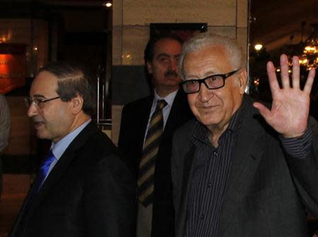 United Nations Peace Envoy for Syria Lakhdar Brahimi (R) waves to journalists during his arrival at a hotel in Damascus October 28, 2013. Seen at left is Syria's Deputy Foreign Minister Faisal al-Miqdad. REUTERS/Khaled al-Hariri