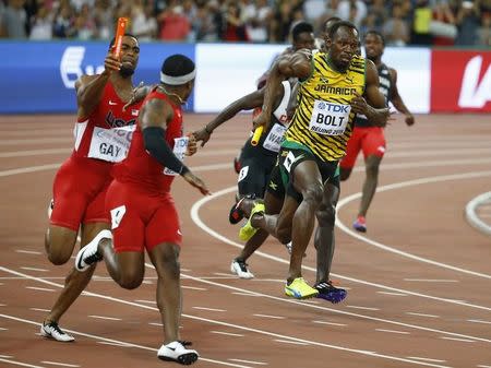 Mike Rodgers of the U.S. (2nd L) receives the baton from his teammate Tyson Gay (L) outside the exchange area as Usain Bolt of Jamaica competes in the men's 4 x 100 metres relay final during the 15th IAAF World Championships at the National Stadium in Beijing, China, August 29, 2015. REUTERS/Damir Sagolj