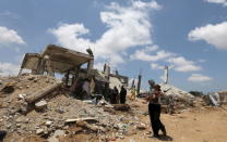 A Palestinian woman holds her daughter as she walks past the ruins of houses, that witnesses said were destroyed by Israeli shelling during a 50-day war last summer, in Khan Younis in the southern Gaza Strip July 2, 2015. REUTERS/Ibraheem Abu Mustafa