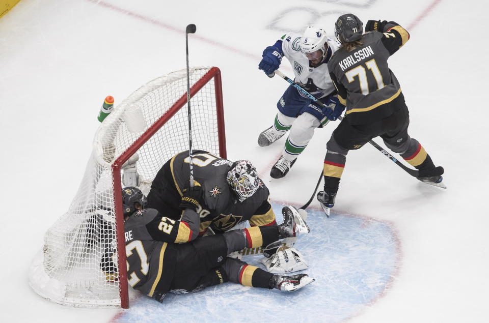 Vegas Golden Knights' Shea Theodore (27) crashes against goalie Robin Lehner (90) as Vancouver Canucks' J.T. Miller (9) and Canucks' William Karlsson (71) battle in front during the third period of Game 2 of an NHL hockey second-round playoff series, Tuesday, Aug. 25, 2020, in Edmonton, Alberta. (Jason Franson/The Canadian Press via AP)