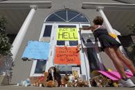 A woman hangs a sign on the front entrance of the River Bluff Dental clinic during a protest against the killing a famous lion in Zimbabwe, in Bloomington, Minnesota July 29, 2015. (REUTERS/Eric Miller)