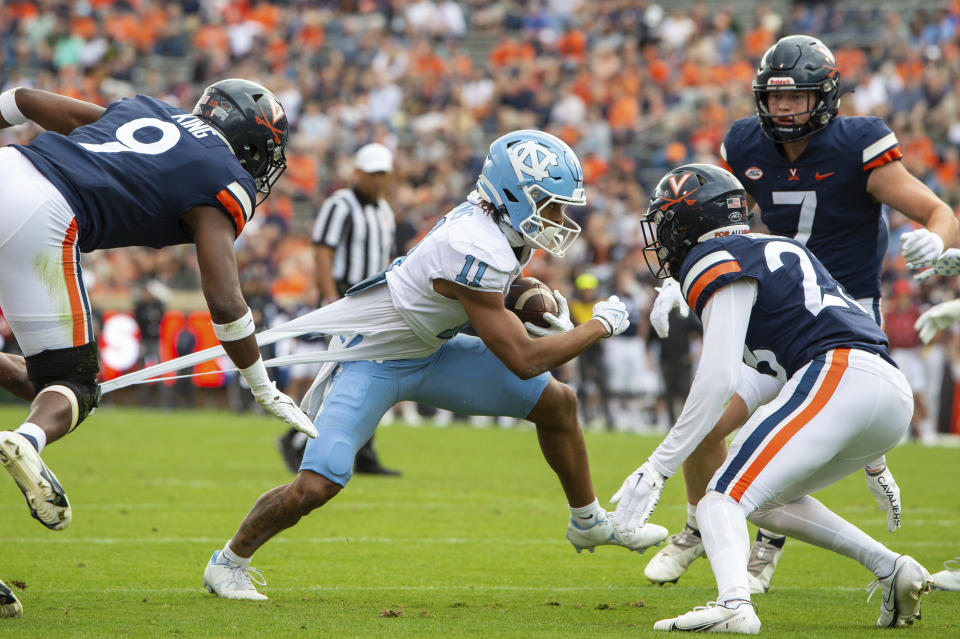 North Carolina wide receiver Josh Downs (11) tries to escape Virginia defensive backs Coen King (9) and Fentrell Cypress II (23) during the first half of an NCAA college football game on Saturday, Nov. 5, 2022, in Charlottesville, Va. (AP Photo/Mike Caudill)