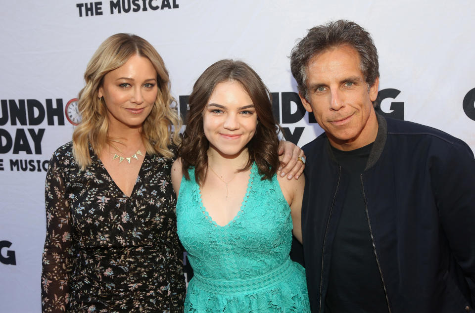 The couple taking a photo with one of their children in between them