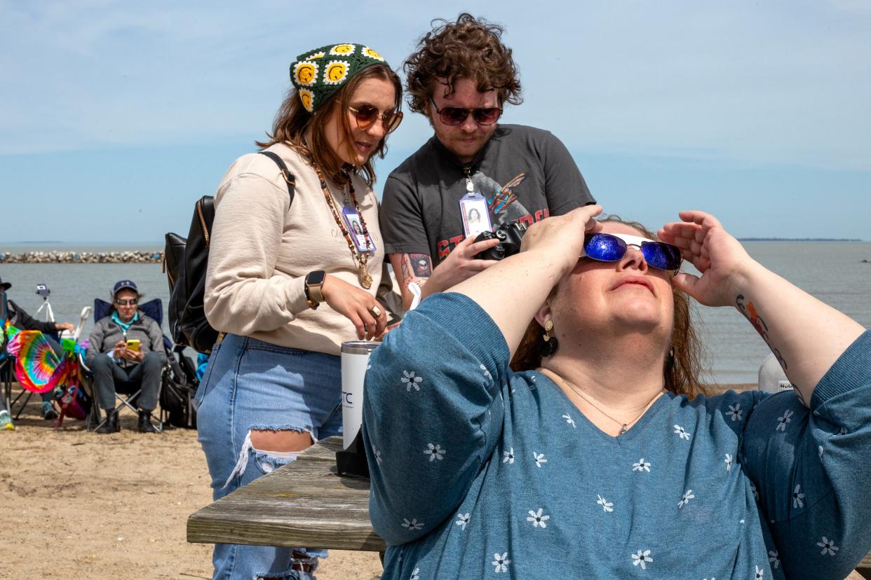 MCCC Agora reporters Destiny Gallina, left, and Mick Valentino review some shots on their camera while Ashley Atkins, assistant editor, uses protective glasses to view the emerging eclipse Monday at East Harbor State Park in Ohio.