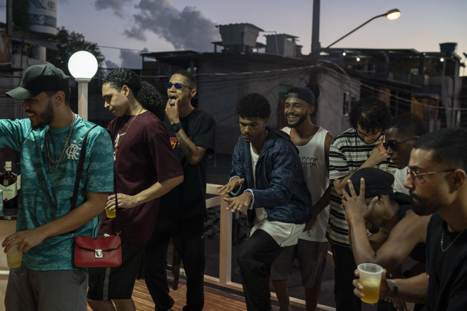 Trap de Cria artists Ramon Silva, known as "Suav," from left, Brendon Oliveira "Trezenit," and Erison de Araujo "DeAra" perform with other artists and friends during the recording of a music video in the Parada de Lucas slum of Rio de Janeiro, Brazil, Sunday, April 4, 2021. Trap de Cria has a lyrical flow over synthesized drums, and is comparable to U.S. gangsta rap in speaking to the day-to-day struggles of hardscrabble hoods while depicting gang life. (AP Photo/Felipe Dana)