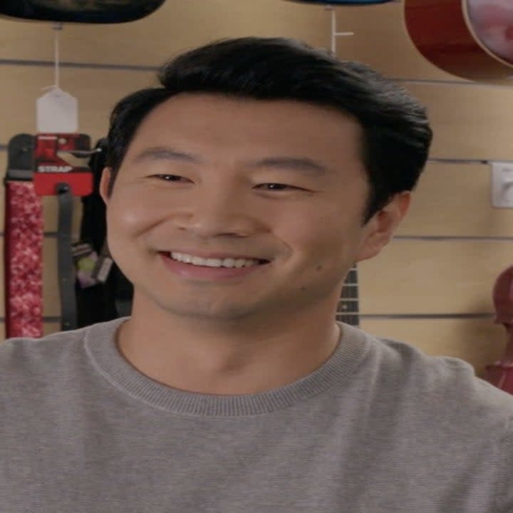 A man smiles standing in front of a row of instruments.