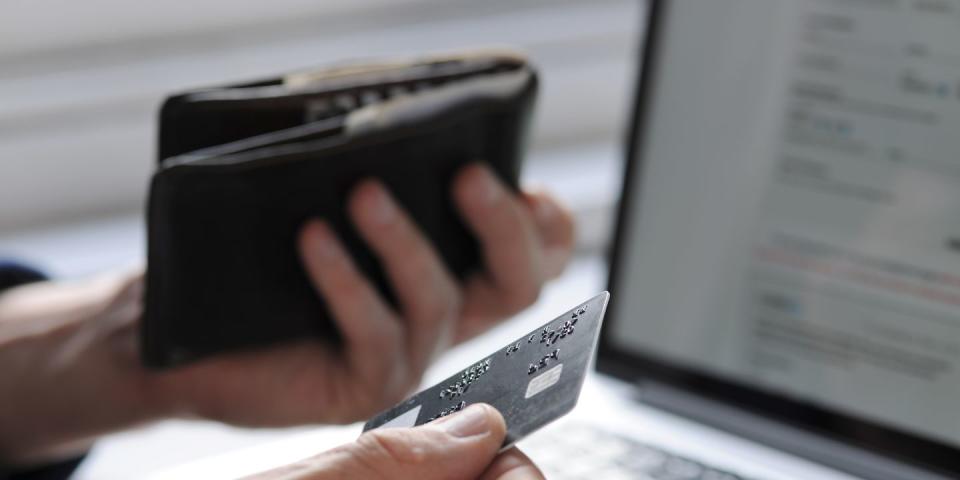 hand holding credit card and wallet by laptop