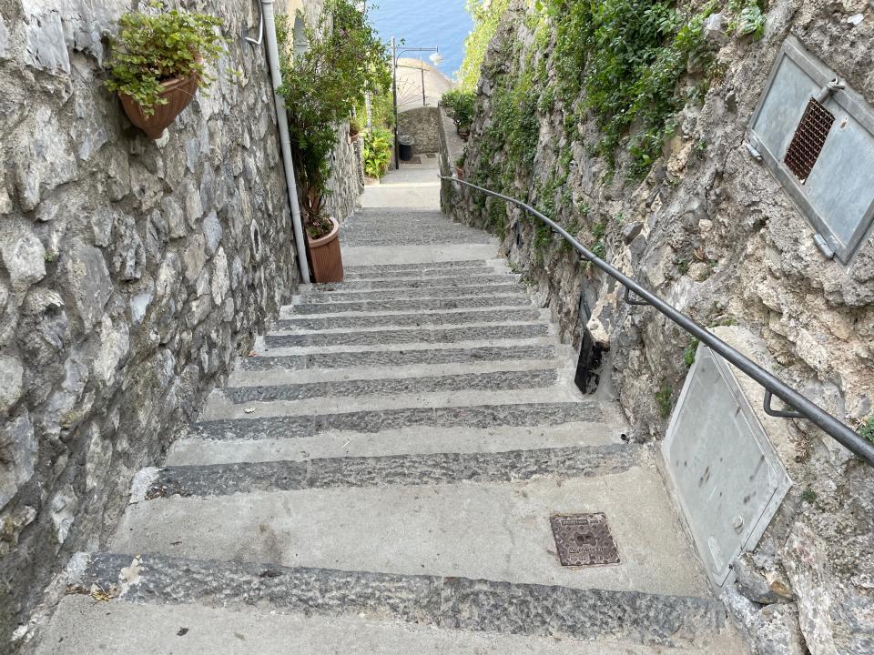 A large amount of steps with a railing on the right and stone walls on each side.
