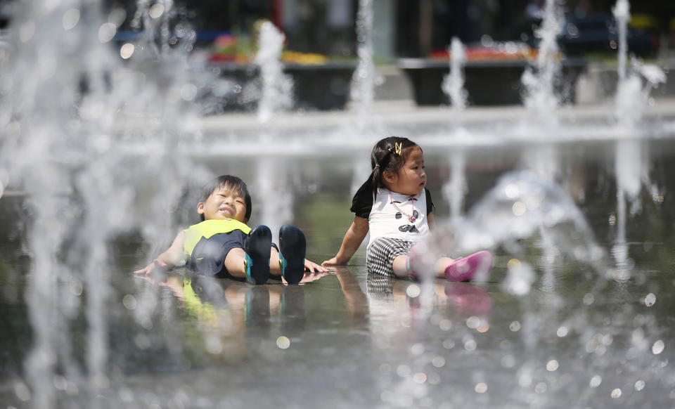 <p>Two children rest in the middle of water shooting from mini-fountains at Gwanghwamun Square in downtown Seoul, South Korea, on May 30, 2016, as the country is gripped by unusually hot weather, with the capital’s daytime high reaching about 82 degrees Fahrenheit. (Yonhap/EPA) </p>