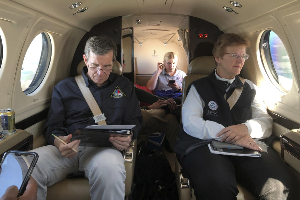 North Carolina Gov. Roy Cooper, left, makes notes on a report as FEMA Coordinating Officer Libby Turner looks out the window of their plane on the way to the coast, Friday, Sept. 6, 2019, over N.C. (AP Photo/Allen Breed, Pool)