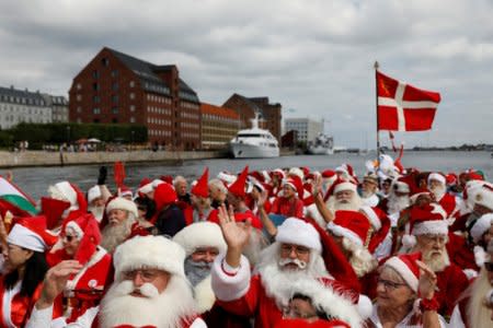 People dressed as Santa Claus wave from a canal boat as they take part in the World Santa Claus Congress, an annual event held every summer in Copenhagen, Denmark, July 23, 2018.  REUTERS/Andrew Kelly