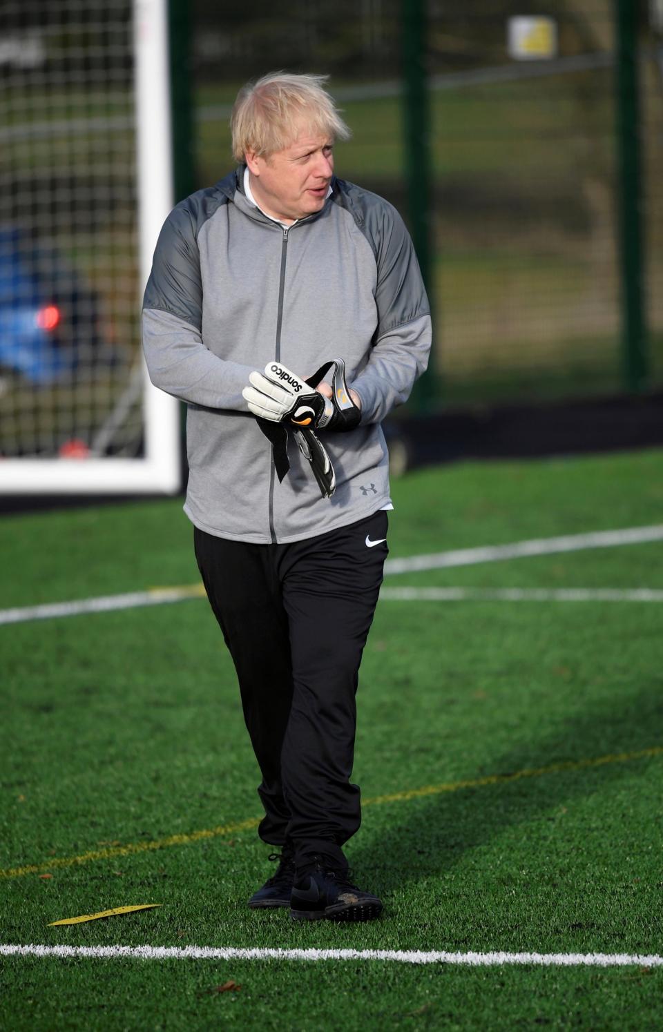 Britain's Prime Minister Boris Johnson puts on goalkeeper gloves as he campaigns in Cheadle Hulme (AP)