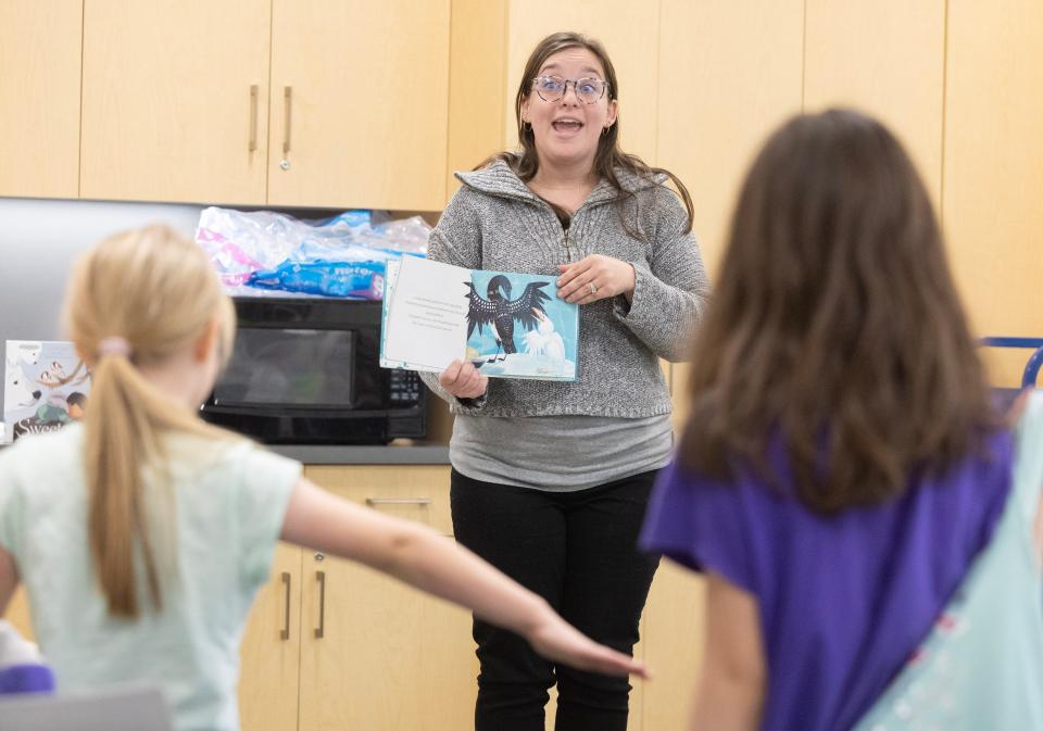 Claire Cross, youth librarian at the Stark Library's Perry Sippo Branch, reads "The Raven and the Loon" as children portray ravens at the Trail Tales/Arctic Animal Legends story and a craft program.