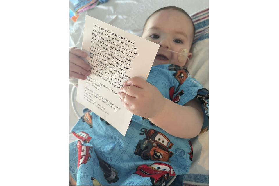 1-year-old Vito DiSimone holds a card that came with the special hospital gown he was given during a stay at NYU Langone Medical Center in New York on Jan. 11, 2024. The gown was made by two New Jersey sisters, Giuliana and Audrina Demma, who have sewn and donated 1,800 brightly-colored and kid-themed hospital gowns to sick children in 36 states and Uganda since 2021. (Samantha DiSimone)