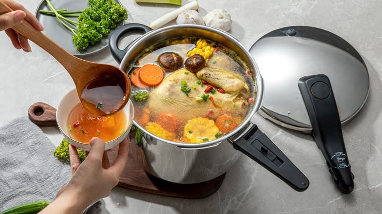 broth ladled into a bowl from a pressure cooker packed with chicken and veg