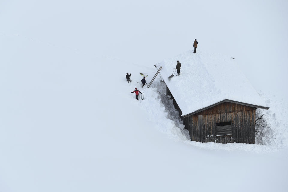 Men clean a roof from snow in Lofer, Austrian province of Salzburg on Friday, Jan. 11, 2019.(AP Photo/Kerstin Joensson)