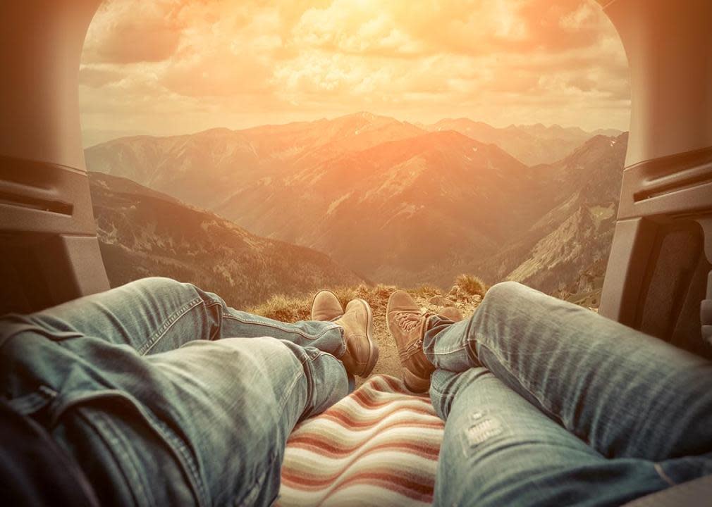 view from the trunk of a car of a sunset, legs of two people laying side-by-side visible 