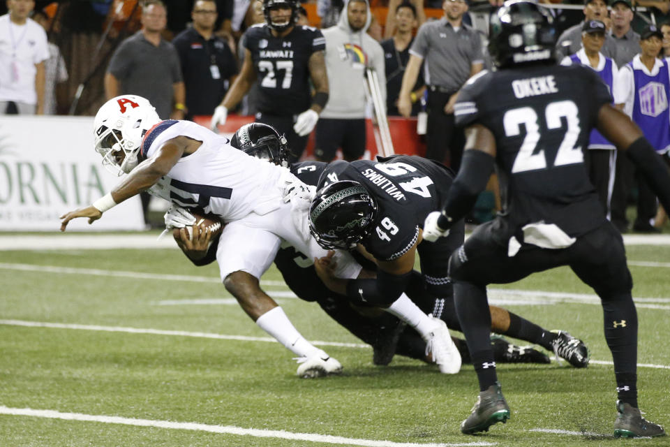 With no time left in the 4th quarter, Hawaii defensive back Kalen Hicks (3) and defensive lineman Manly Williams (49) tackle Arizona quarterback Khalil Tate (14) just short of the end zone during an NCAA college football game, Saturday, Aug. 24, 2019, in Honolulu. (AP Photo/Marco Garcia)