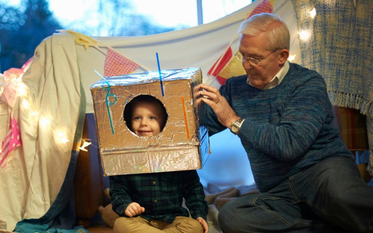 Senior man putting robot costume on grandson