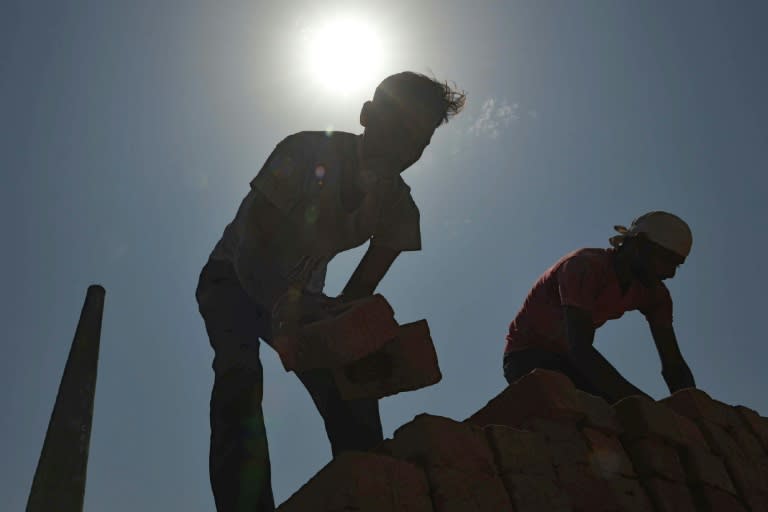 This photograph taken on September 16, 2017, shows Indian labourers loading bricks onto a tractor trolley at a brick kiln on the outskirts of Amritsar