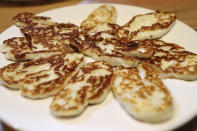 In this photo taken Wednesday Dec. 11, 2019, Cyprus' halloumi cheese is seen roasted on a plate at "Riverland" farm in Kampia village near Nicosia, Cyprus. Cyprus' halloumi cheese, with a tradition dating back some five centuries, is the island nation's leading export. It's goat and sheep milk content makes it a hit with health-conscious cheese lovers in Europe and beyond. It's added appeal is that unlike other cheeses, it doesn't melt when heated up. (AP Photo/Petros Karadjias)